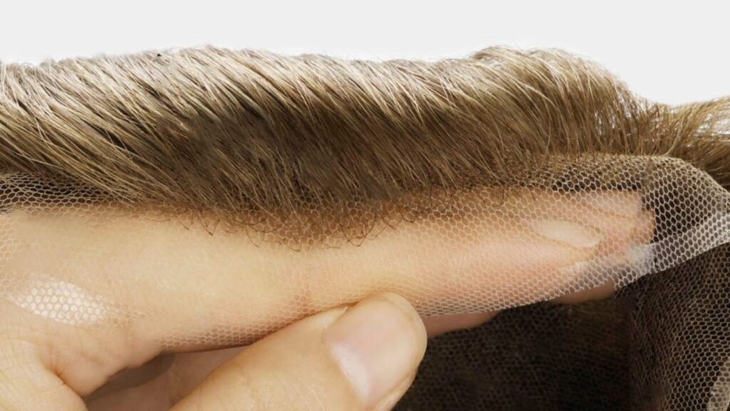 A finger is holding the front hairline of a toupee hairpiece